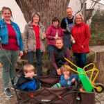 Gruppenbild mit Freiwilligen und Kindern in Bollerwagen