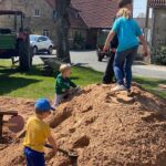 Kinder helfen beim Sand schaufeln bei der Spielplatzaktion