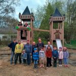Freiwillige Helfer der Aktion 2026 vor Holz-Spielburg